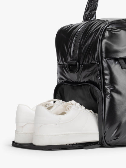 Black duffel bag shoe compartment on a white background; CALPAK Luka Duffel in shiny black on a white background; DSM1901-GLAZED-BLACK