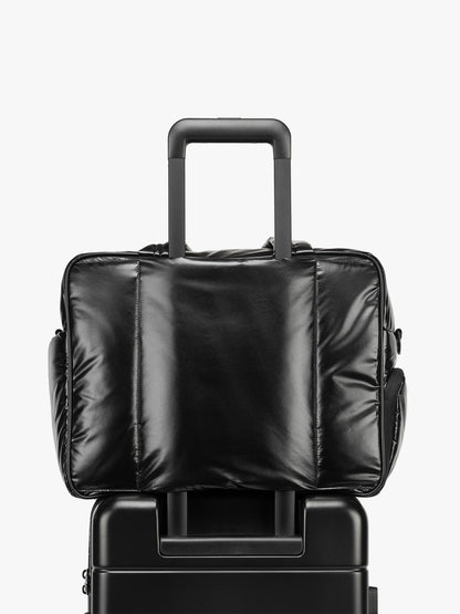 CALPAK Luka Duffel in shiny black on a white background with luggage sleeve; DSM1901-GLAZED-BLACK