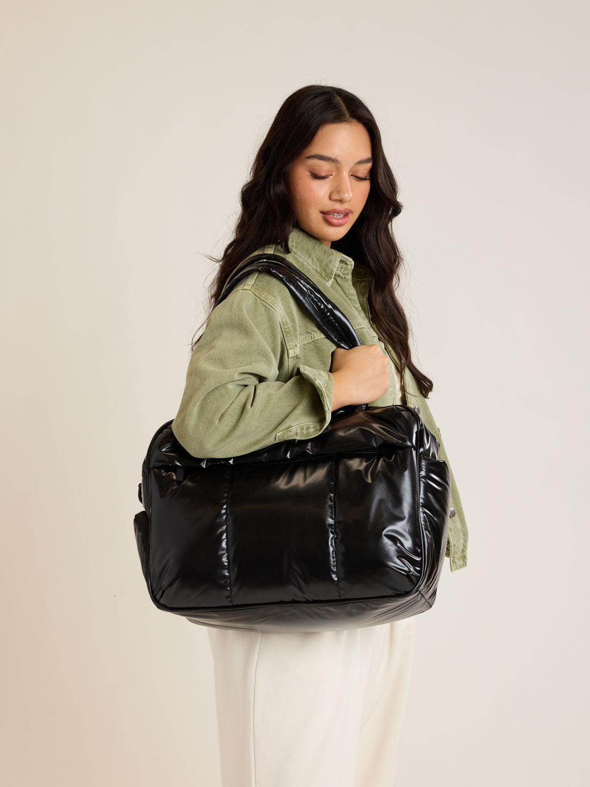 Model weraing CALPAK Luka Duffel in shiny black on a white background; DSM1901-GLAZED-BLACK