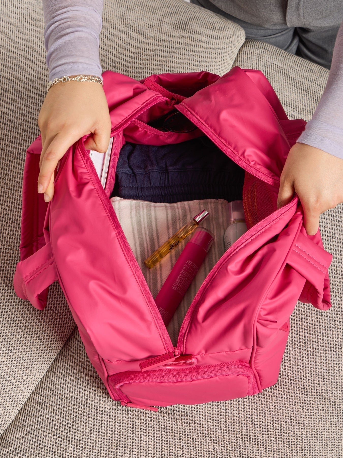 Model showing the monochrome dragonfruit pink interior of CALPAK luka duffel; DSM1901-DRAGONFRUIT