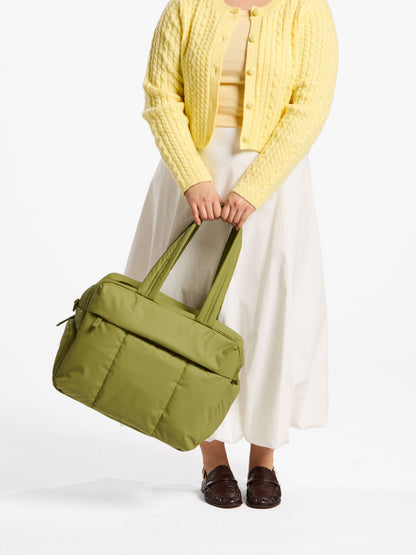 Model holding CALPAK luka duffel by straps in green; DSM1901-PISTACHIO