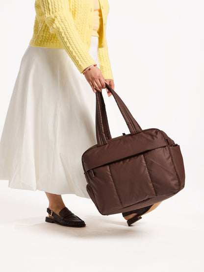 Model holding CALPAK Luka Duffel by handle in dark brown; DSM1901-WALNUT
