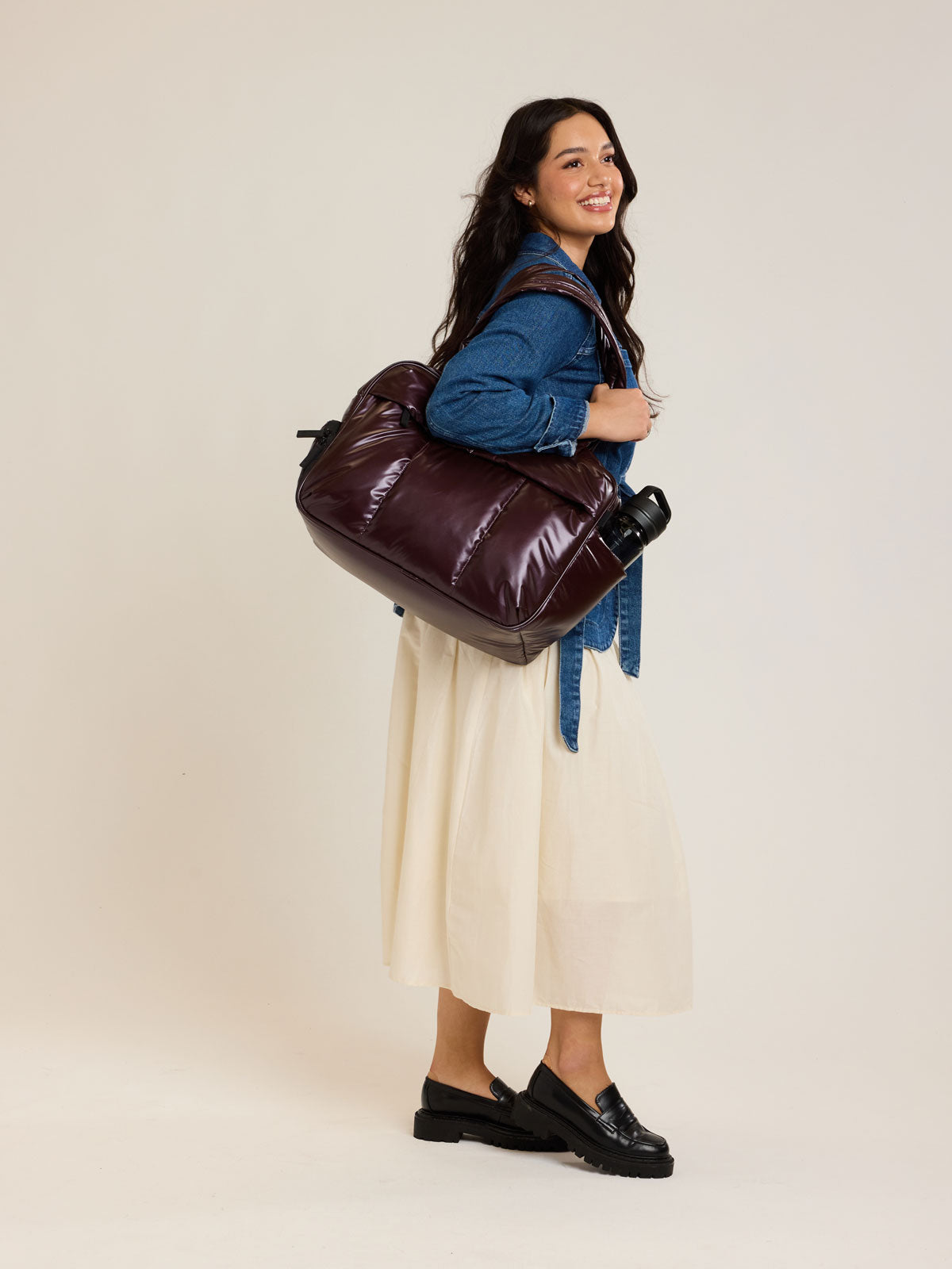 Model with CALPAK Dark Cherry red Luka Duffel front view on a white background; DSM1901-GLAZED-DARK-CHERRY