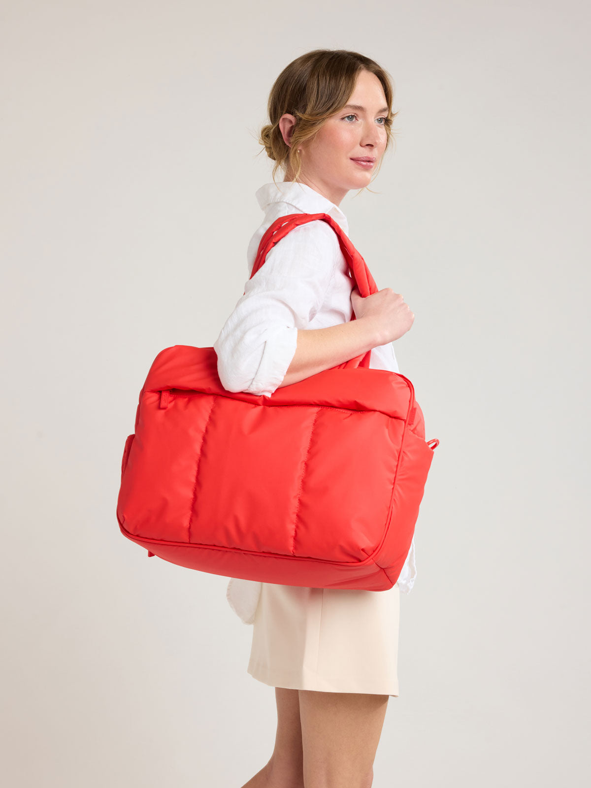 Person with CALPAK Luka Duffel in red Tomato; DSM1901-TOMATO