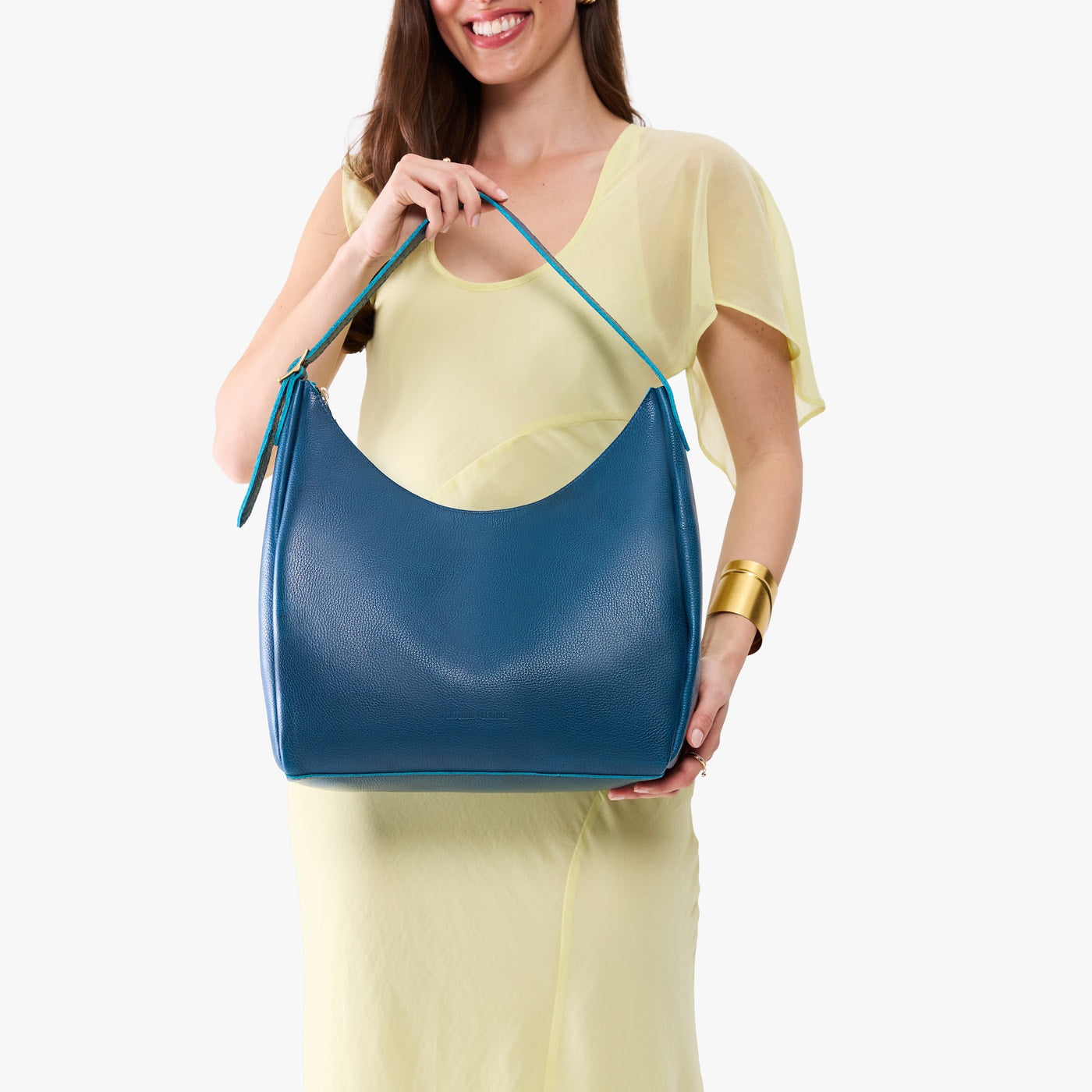 Caspian*Large | Model holding u-shaped, flat-bottomed leather shoulder bag with adjustable strap