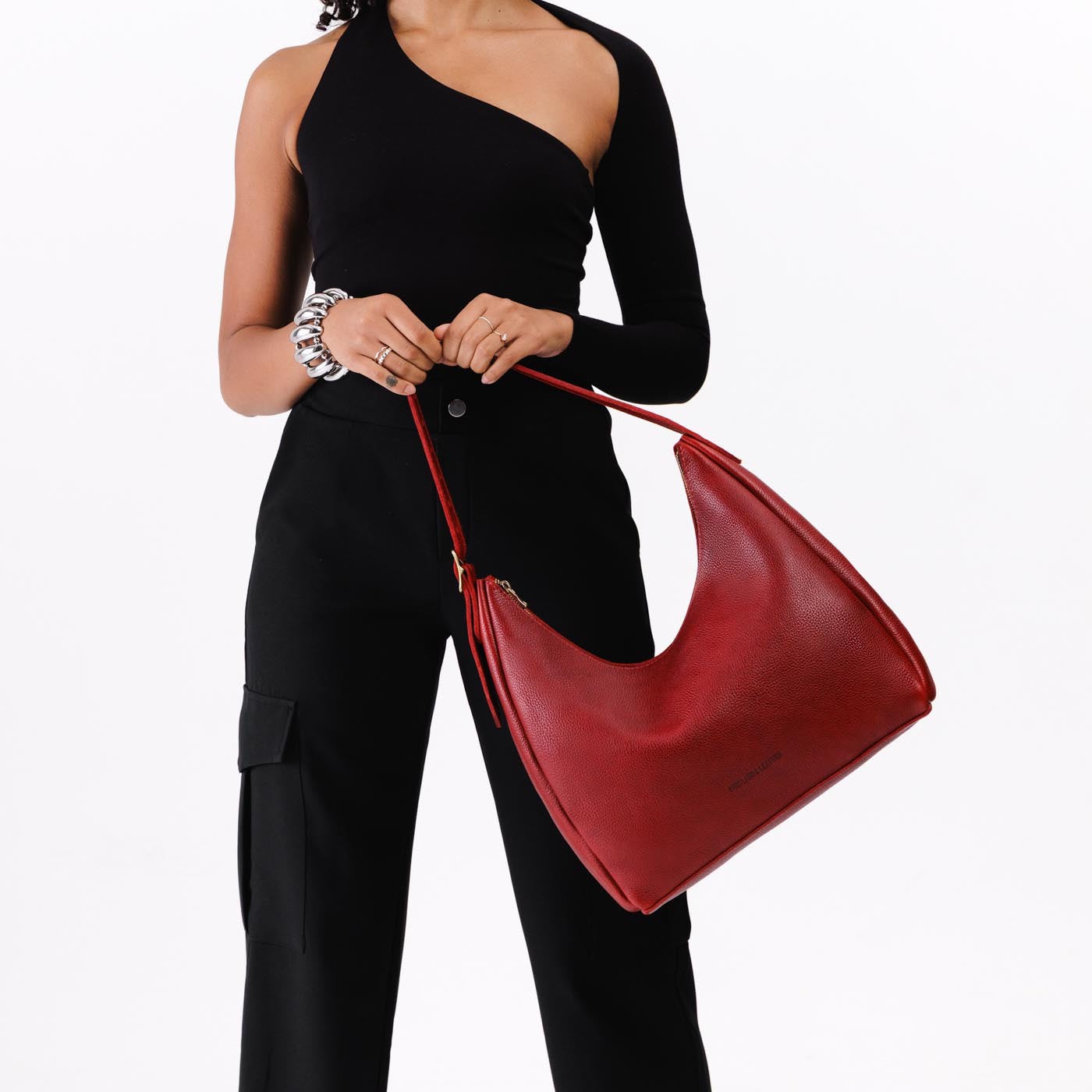 Chili Red*Large | Model holding u-shaped, flat-bottomed leather shoulder bag with adjustable strap