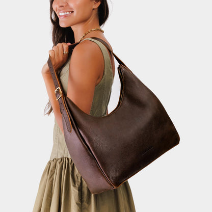 Coldbrew*Large | Model holding u-shaped, flat-bottomed leather shoulder bag with adjustable strap
