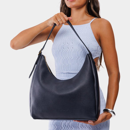 Night Owl*Large | Model holding u-shaped, flat-bottomed leather shoulder bag with adjustable strap