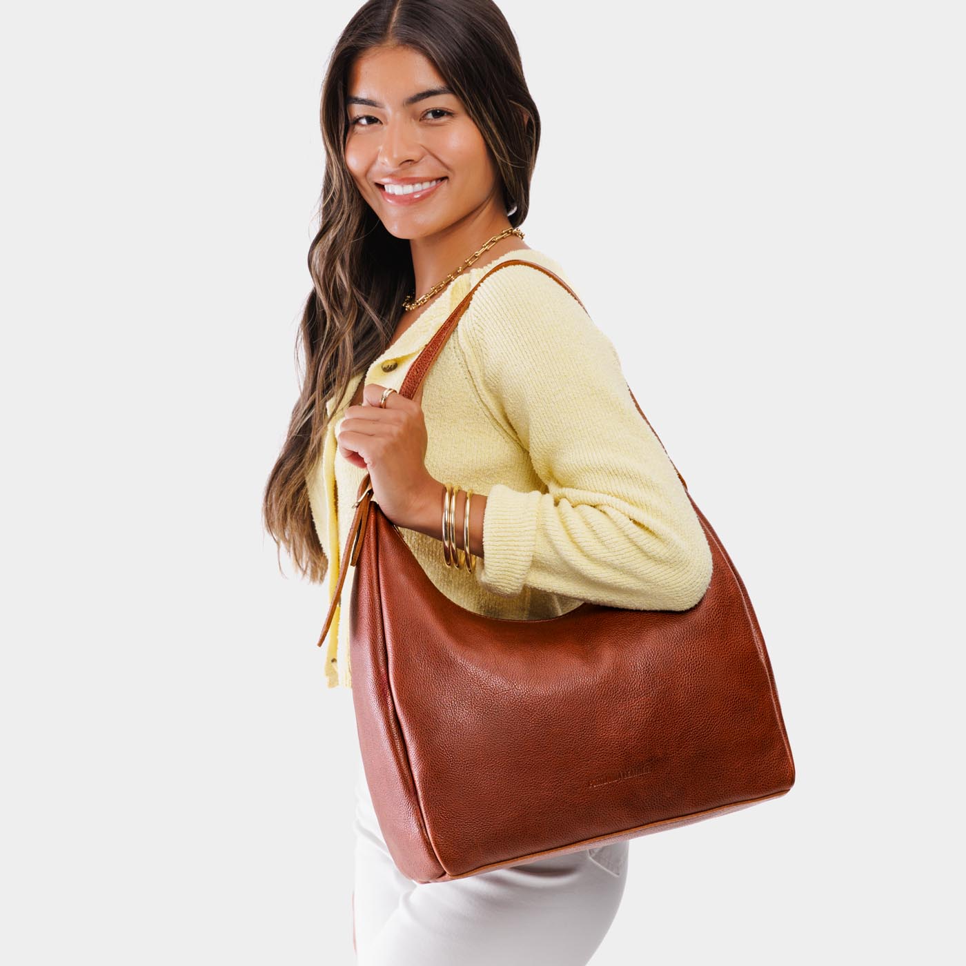 Nutmeg*Large | Model holding u-shaped, flat-bottomed leather shoulder bag with adjustable strap
