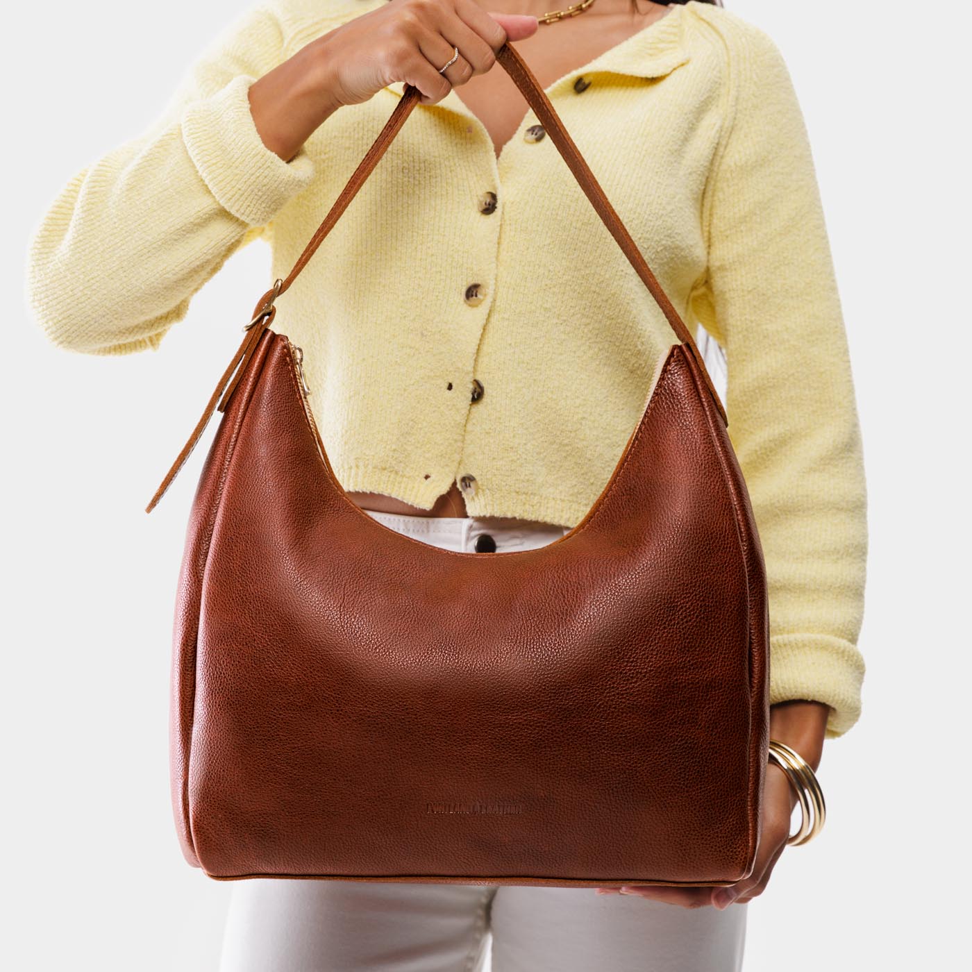 Nutmeg*Large | Model holding u-shaped, flat-bottomed leather shoulder bag with adjustable strap