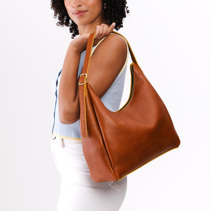 Sienna*Large | Model holding u-shaped, flat-bottomed leather shoulder bag with adjustable strap