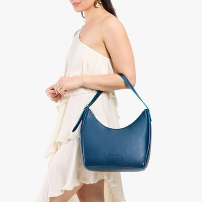Caspian*Medium | Model holding u-shaped, flat-bottomed leather shoulder bag with adjustable strap
