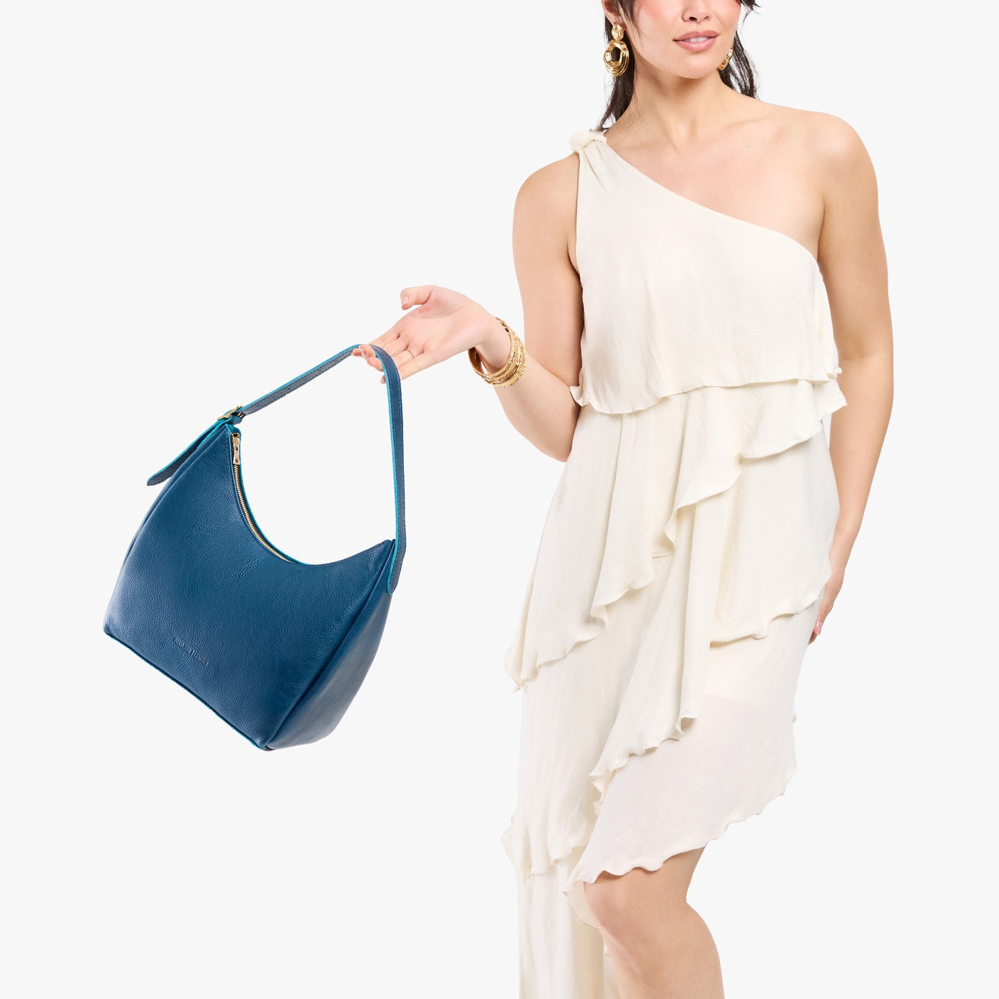 Caspian*Medium | Model holding u-shaped, flat-bottomed leather shoulder bag with adjustable strap