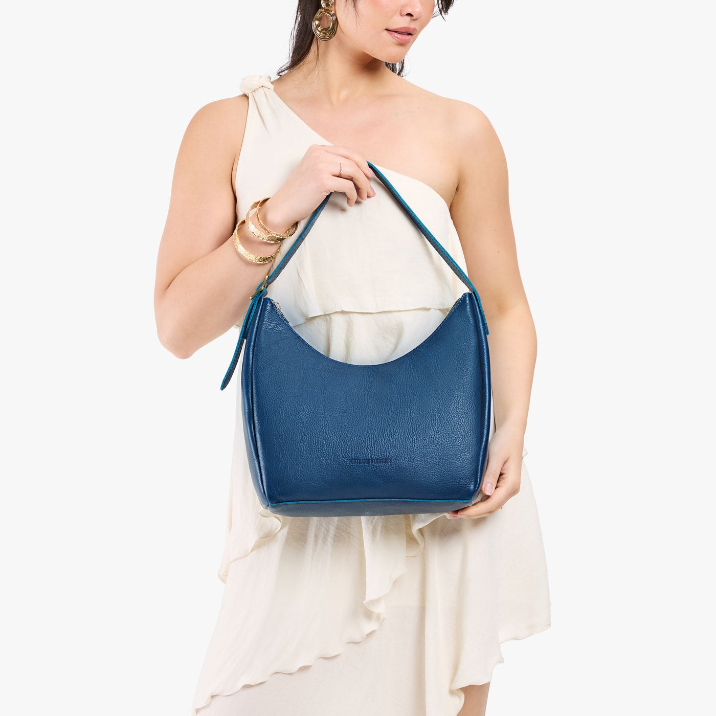 Caspian*Medium | Model holding u-shaped, flat-bottomed leather shoulder bag with adjustable strap