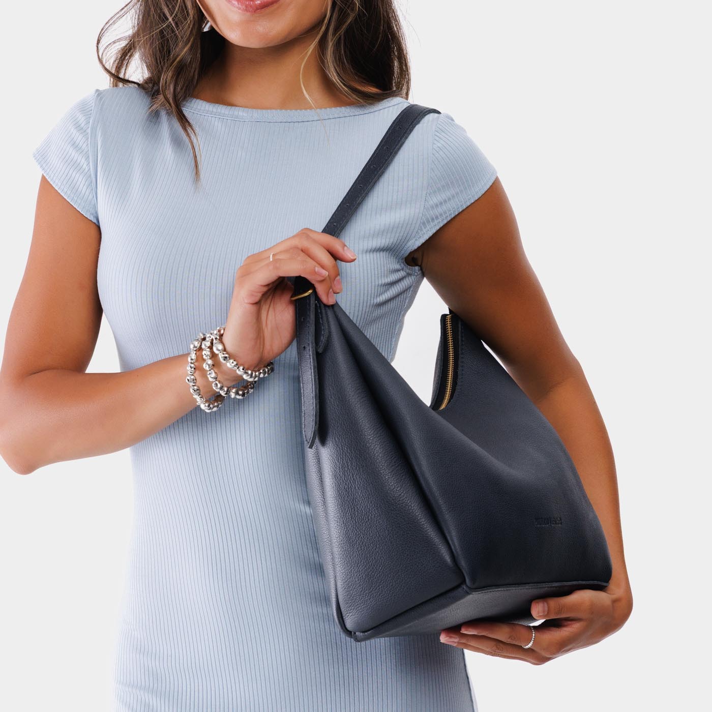 Night Owl*Medium | Model holding u-shaped, flat-bottomed leather shoulder bag with adjustable strap